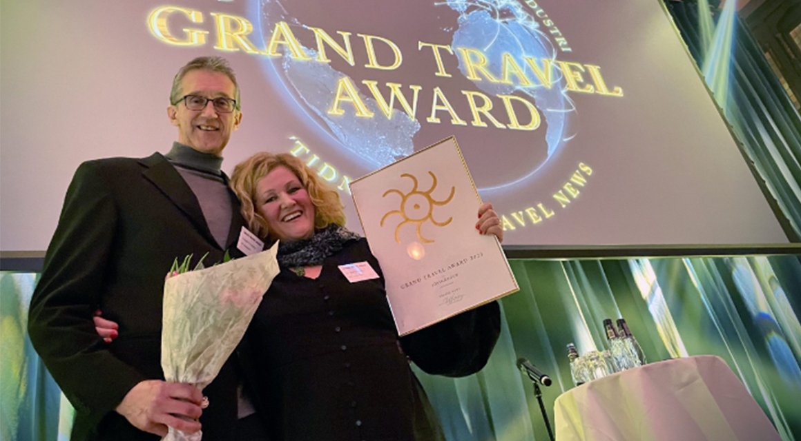 Helene och Torbjörn håller leende upp blommor och plakett vid prisutdelning